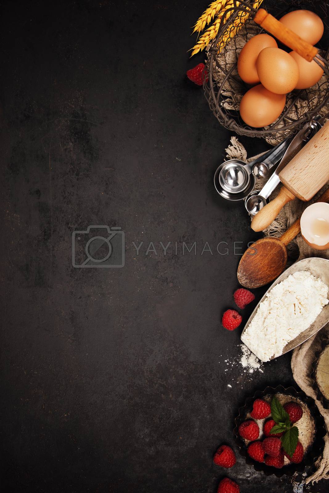 Baking tools and ingredients - flour, eggs, rolling pin, measuring spoons  on vintage table. Top view. Rustic background with free text space
