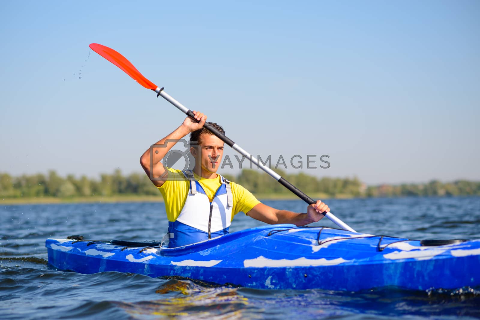 Royalty free image of Young Professional Kayaker Paddling Kayak on River under Bright Morning Sun. Sport and Active Lifestyle Concept by maxpro
