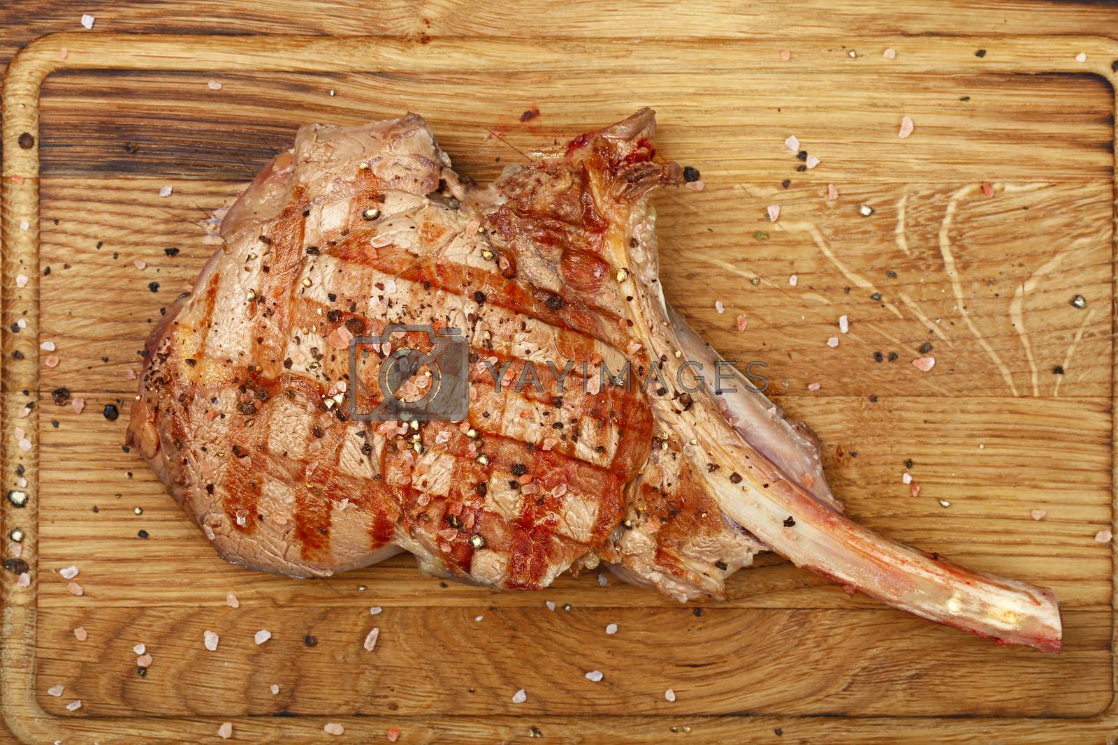 Royalty free image of Close up grilled beef steak on wooden board by BreakingTheWalls