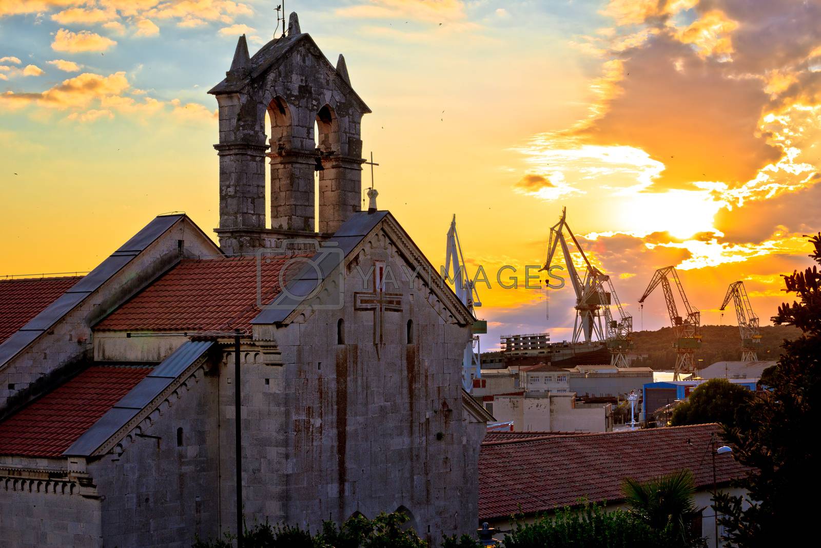 Royalty free image of Town of Pula stone church and shipyard cranes sunset view by xbrchx