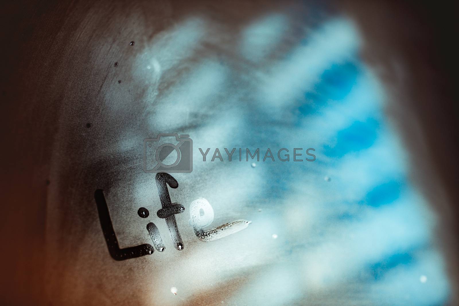 Closeup photo of a misted-up window with written word on it, abstract blurry background, conceptual photo of life