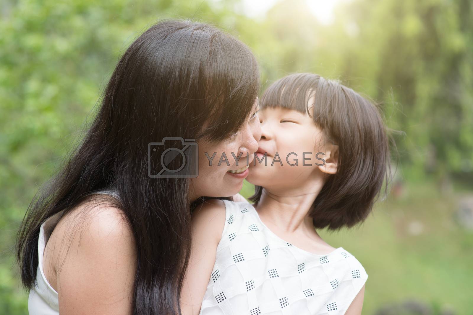 Royalty free image of Little girl kissing mom at outdoor park by szefei