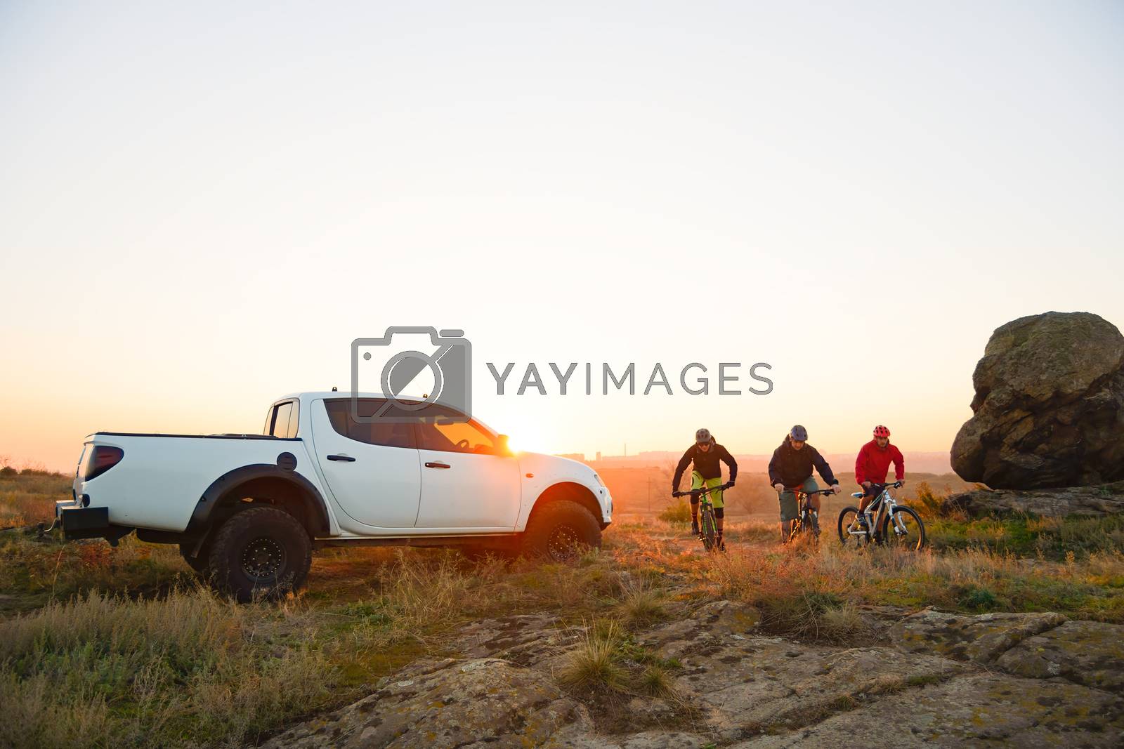 Royalty free image of Friends Riding Bikes in the Mountains in front of the Pickup Off Road Truck at Sunset. Adventure and Travel Concept by maxpro