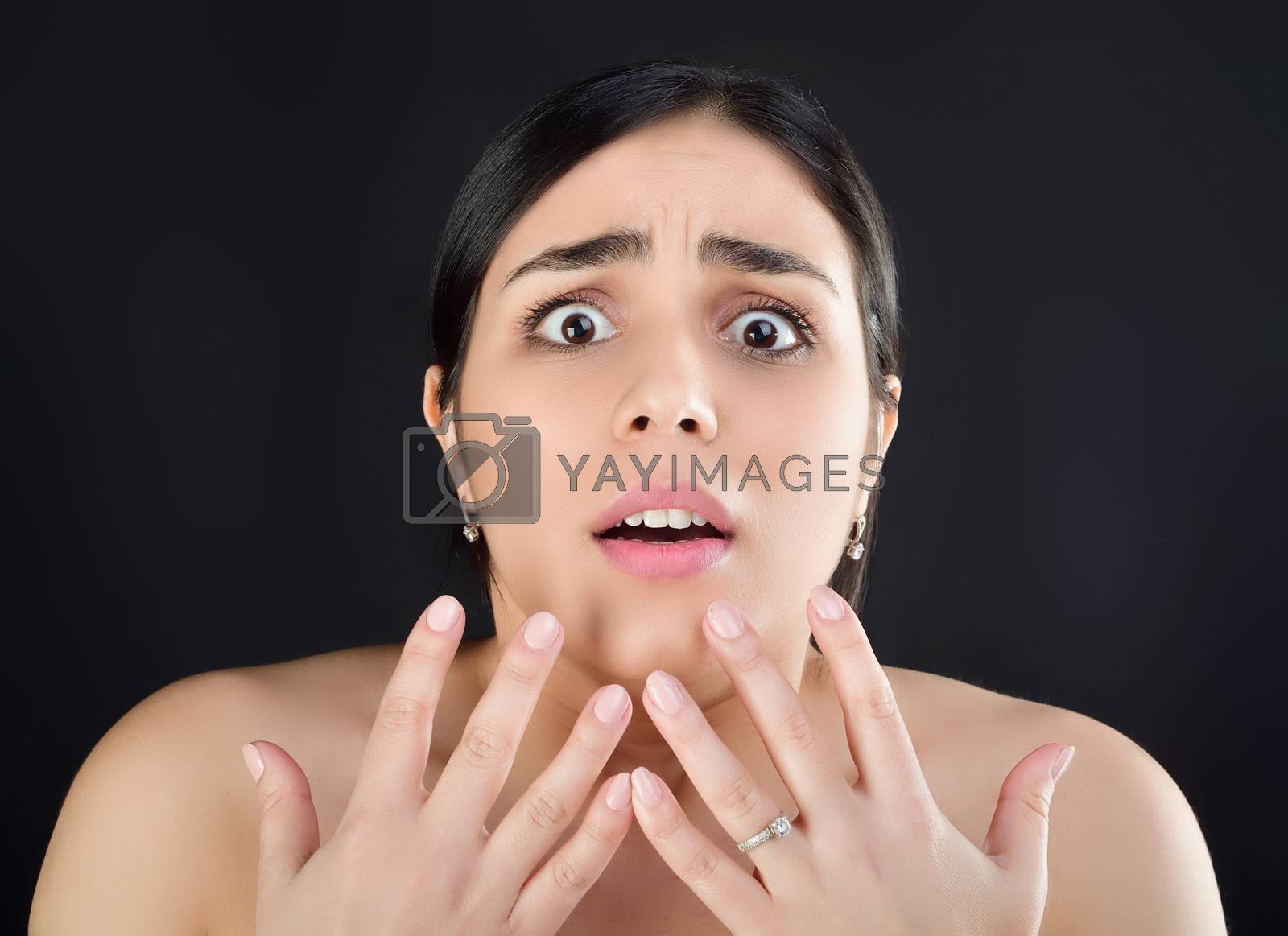 Royalty free image of Beauty portrait of a girl with fingers near her face who looks at the camera with fear or surprise by xzgorik