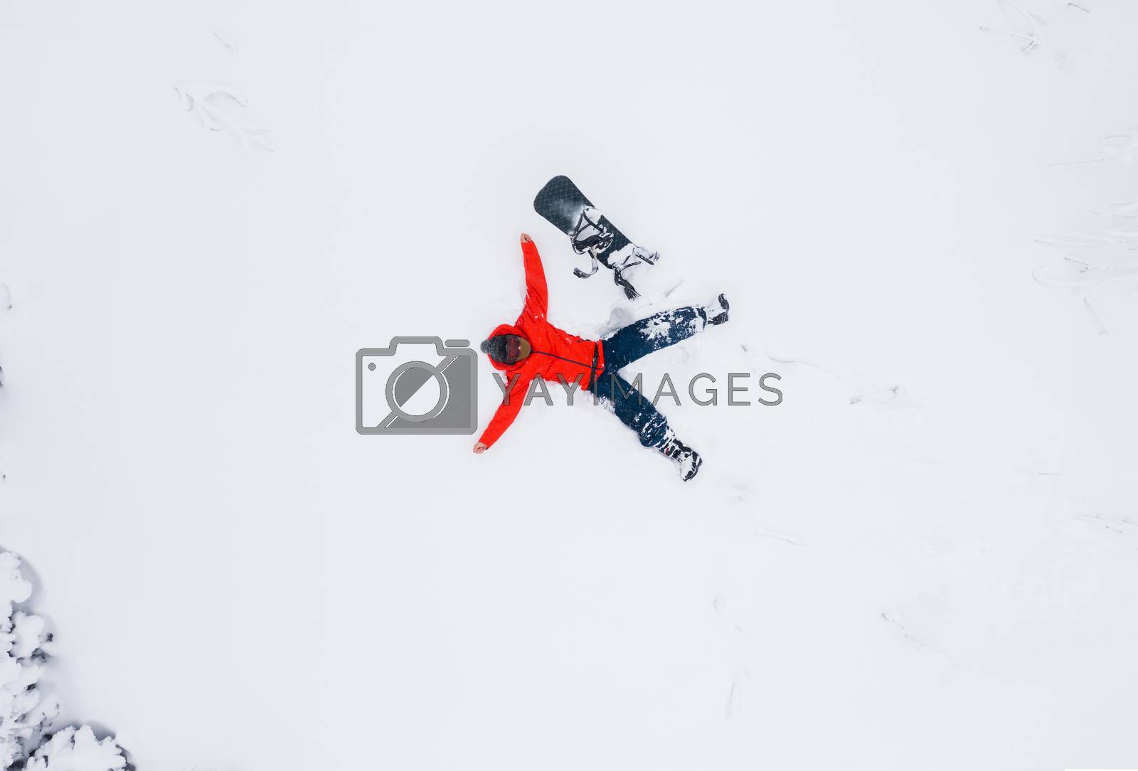 Royalty free image of Aerial view of a man lying in the snow next to his snowboard by vlad_star