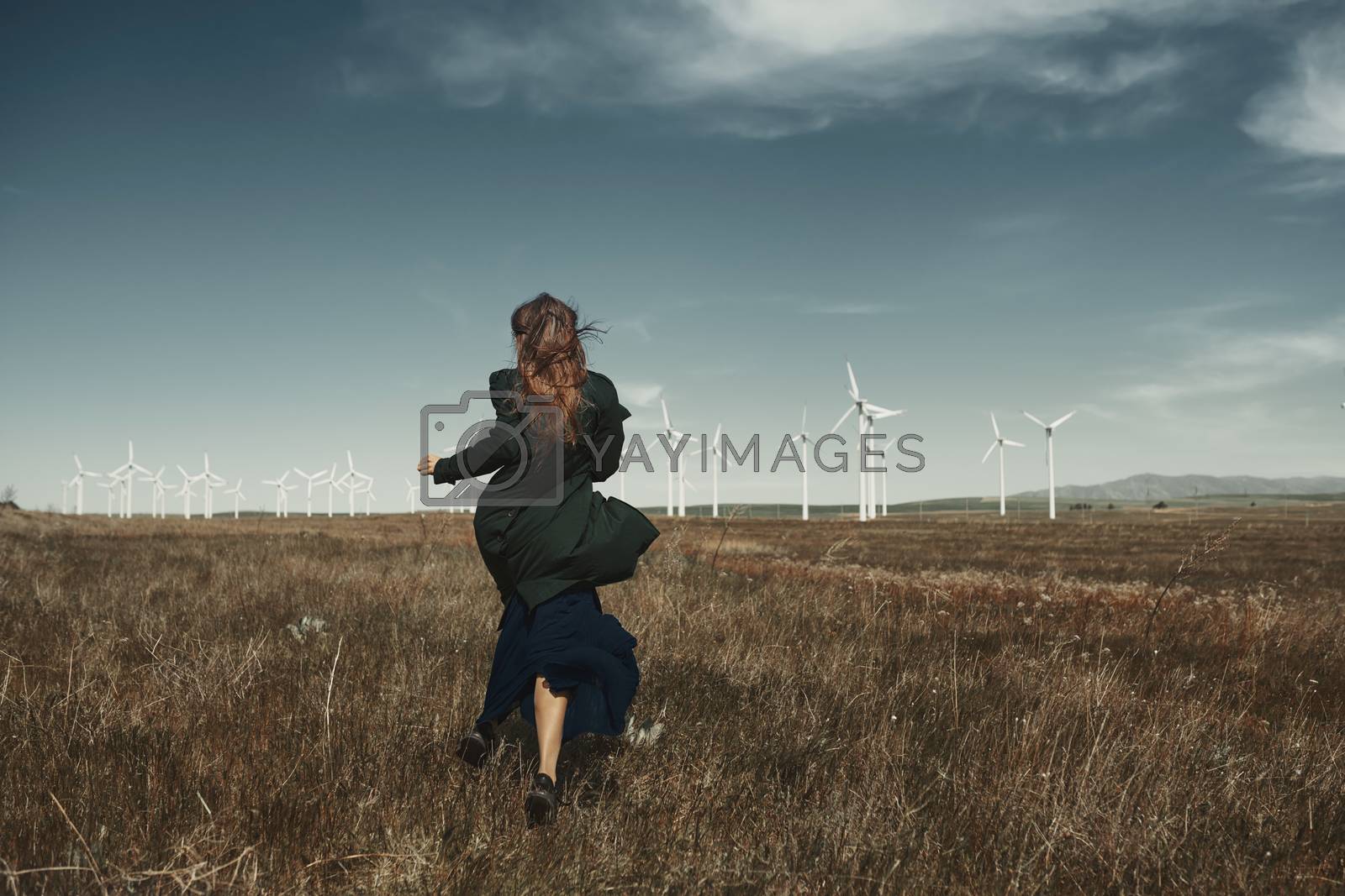 Royalty free image of Woman with long tousled hair next to the wind turbine with the w by Novic