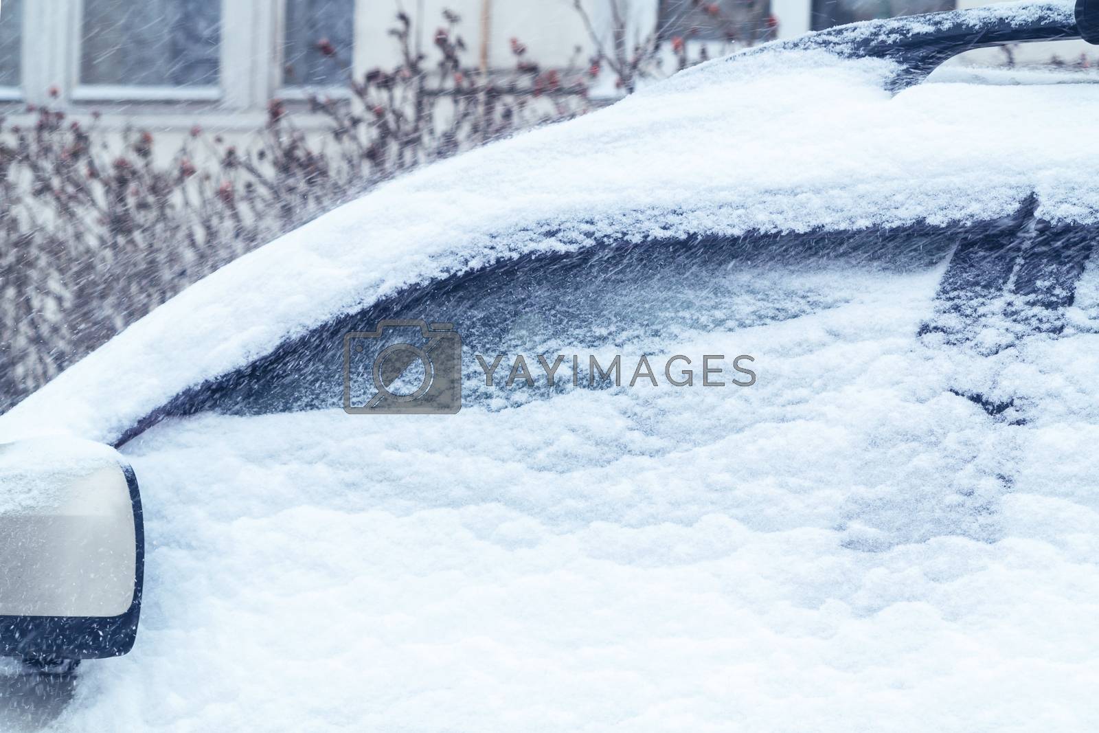 Royalty free image of Snowfall in the city, part of the car covered by snow by galsand