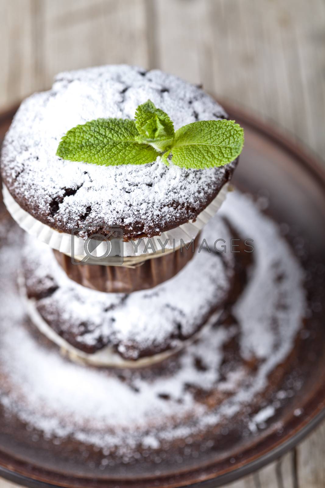Royalty free image of Fresh chocolate dark muffins with sugar powder and mint leaf on  by marylooo