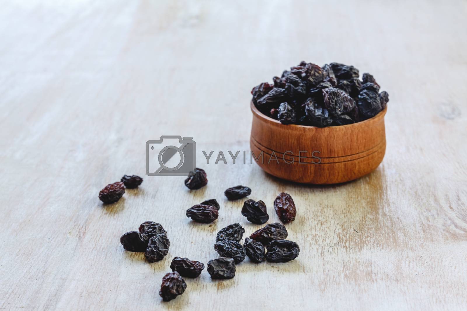 Royalty free image of Dark blue raisins in a wooden bowl on a bright white background. by Tanacha