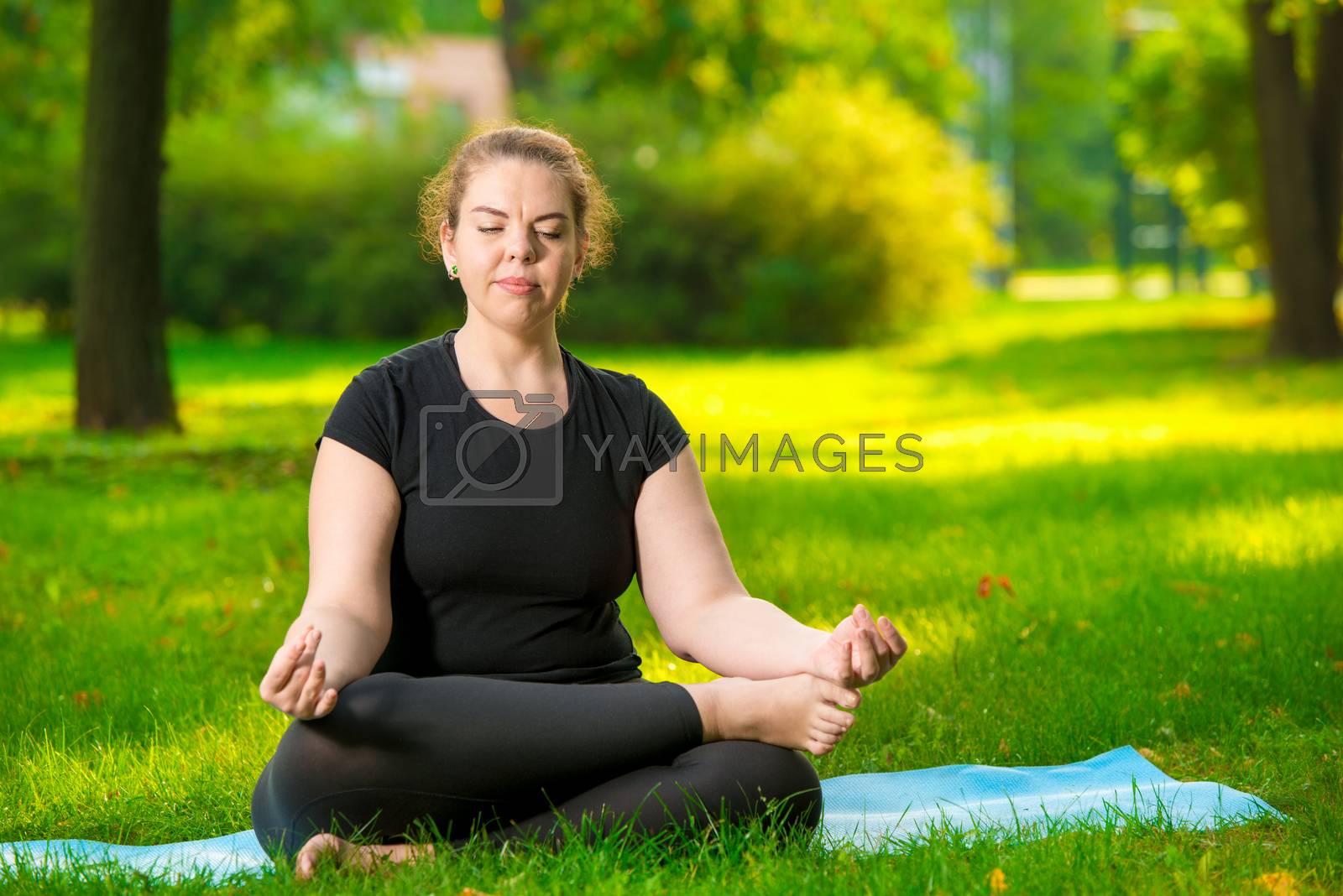 Royalty free image of flexible and concentrated woman oversize is meditating on the la by kosmsos111