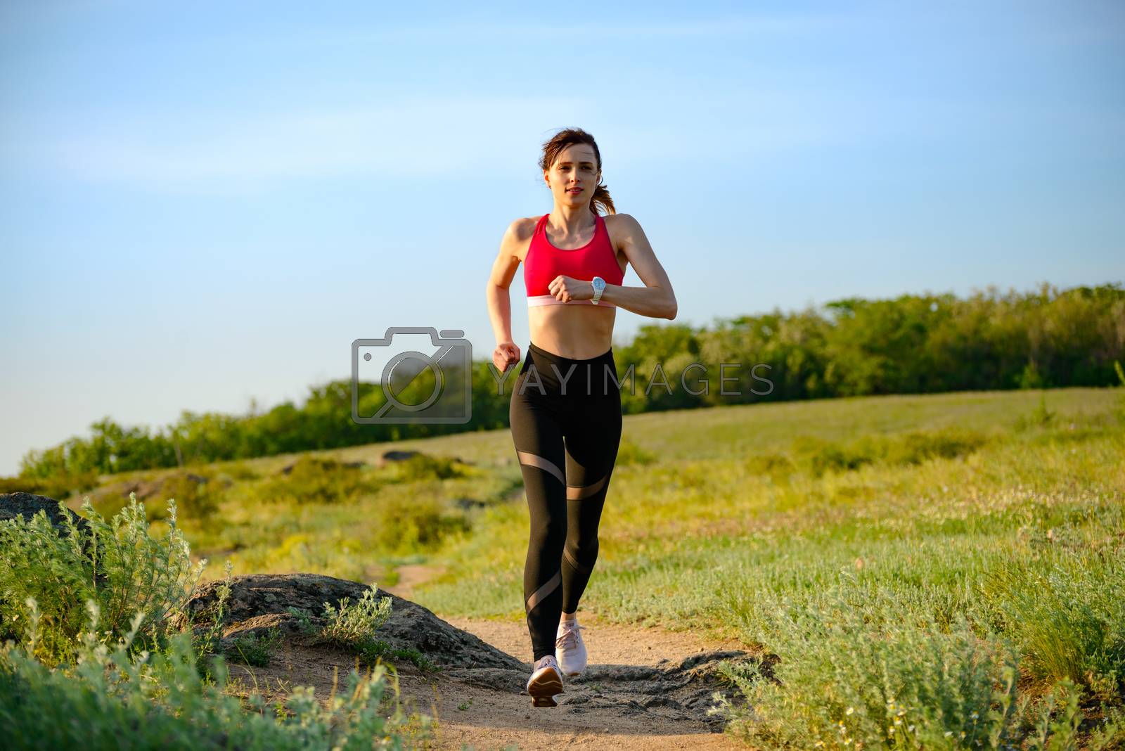 Royalty free image of Young Beautiful Woman Running on the Mountain Trail in the Hot Summer Evening. Sport and Active Lifestyle. by maxpro
