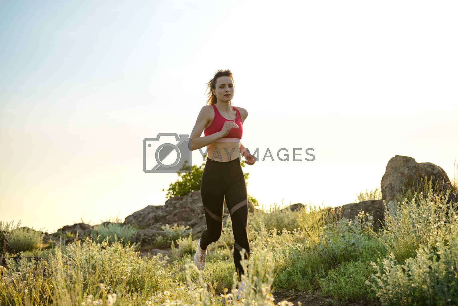 Royalty free image of Young Beautiful Woman Running on the Mountain Trail in the Hot Summer Evening. Sport and Active Lifestyle. by maxpro