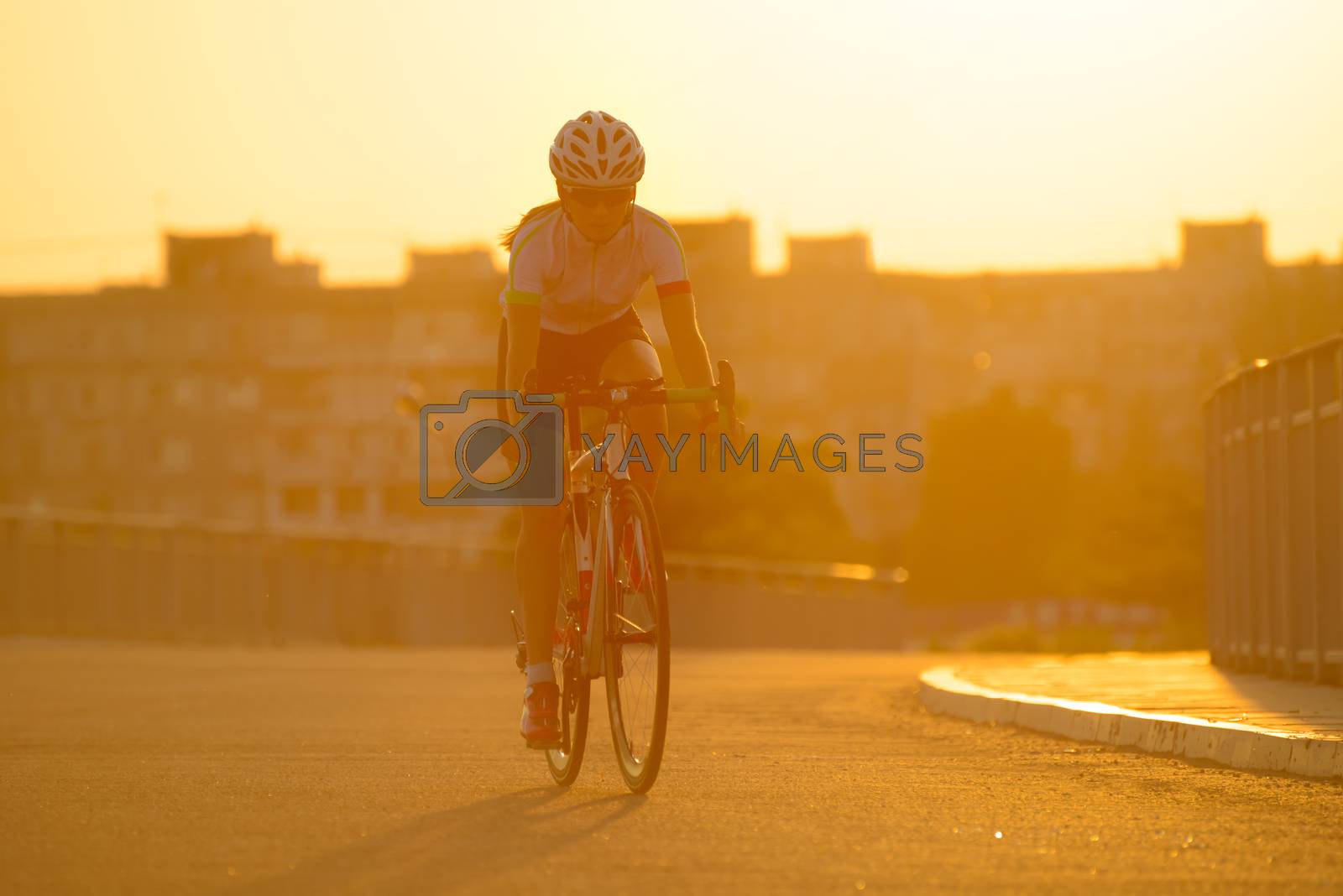 Royalty free image of Young Woman Riding Road Bicycle on Free Street in the City at Sunset. Healthy Lifestyle and Sport Concept. by maxpro