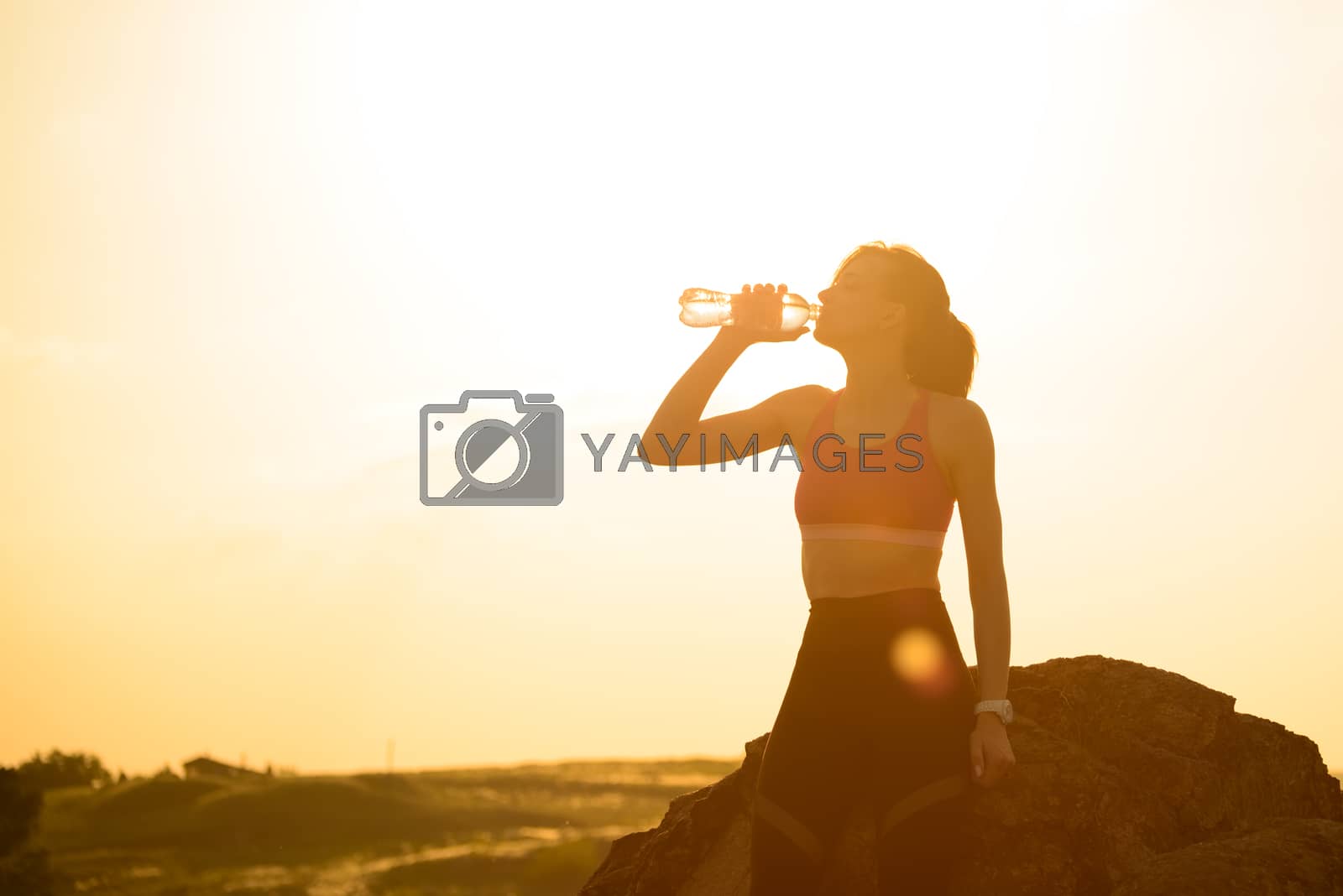 Royalty free image of Woman Resting and Drinking Water after Running Outdoor. Workout at Hot Summer Sunset. Sport and Healthy Active Lifesyle. by maxpro