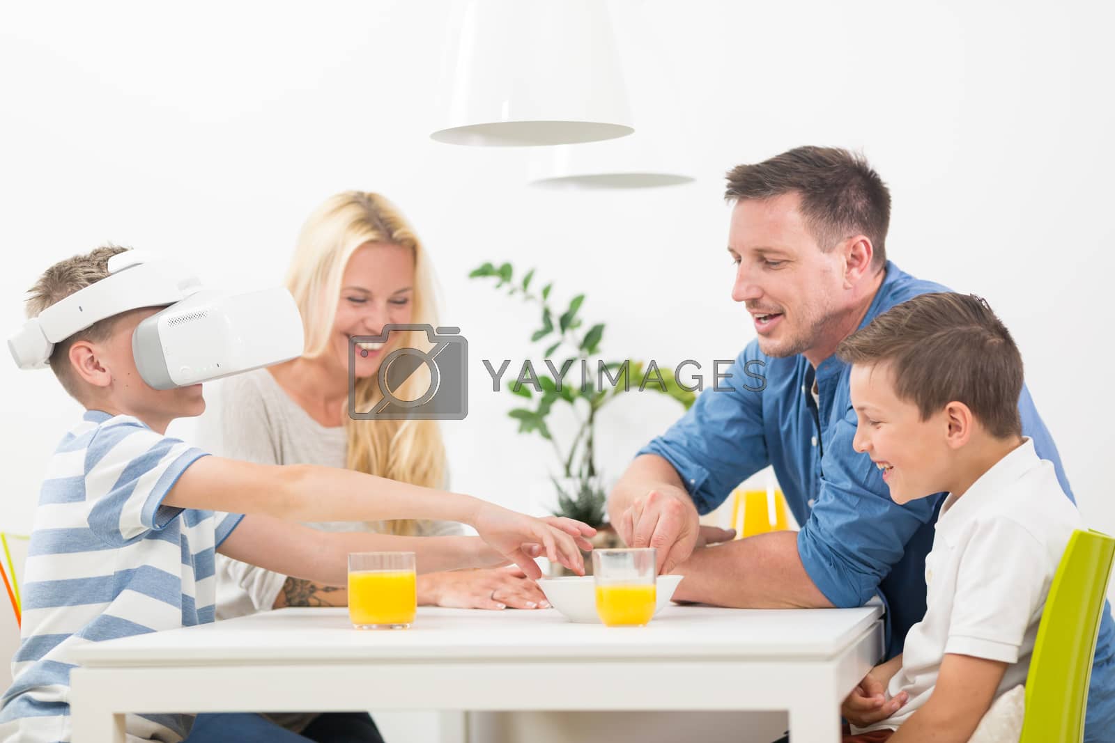 Royalty free image of Happy family at home on living room sofa having fun playing games using virtual reality headset by kasto