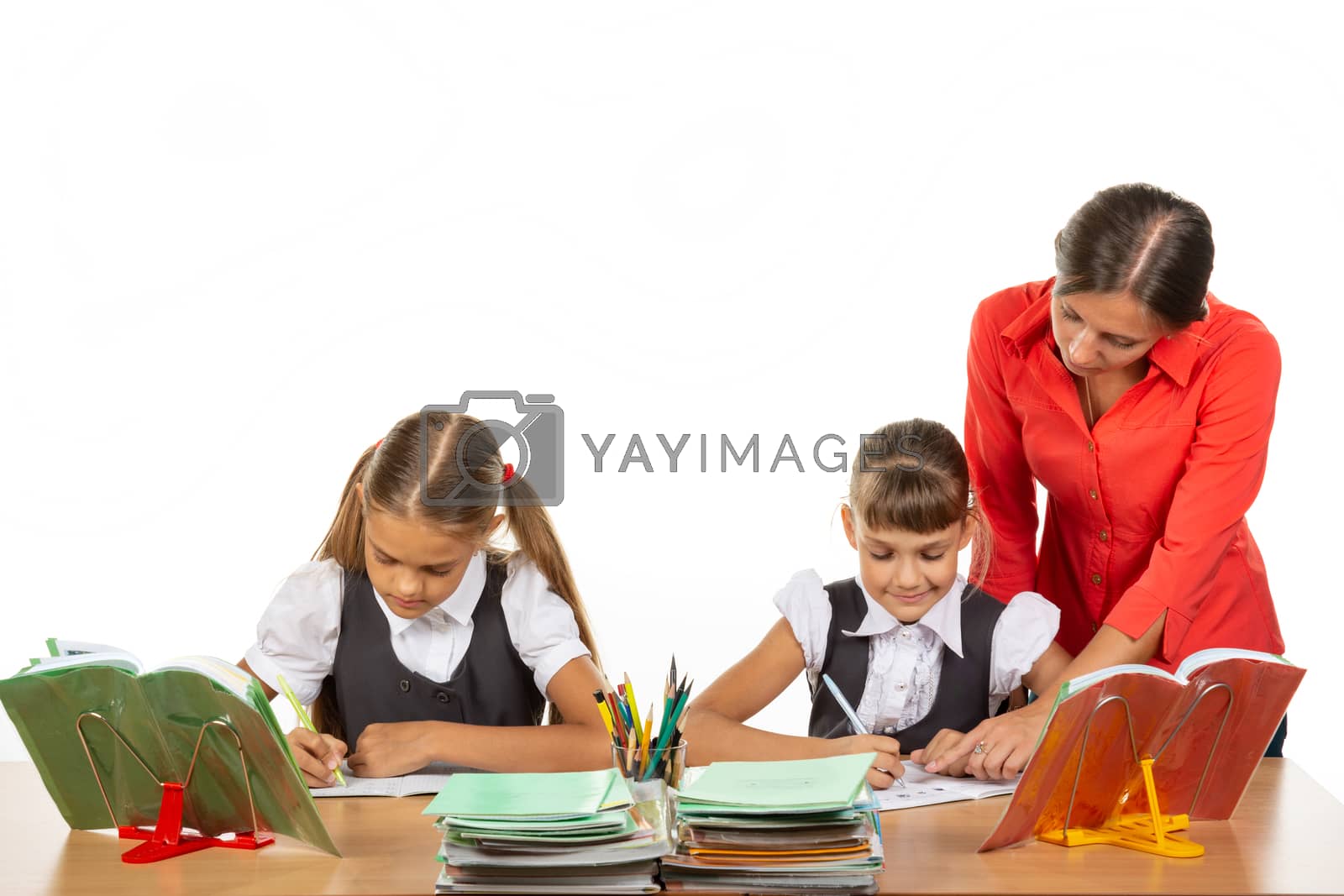 Royalty free image of The teacher goes around the students, looks in the notebook, the students solve the task by Madhourse