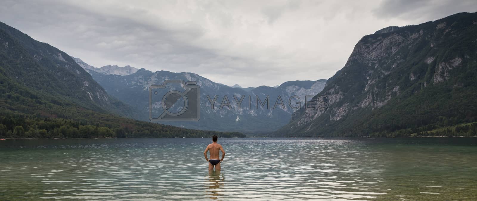 Royalty free image of Man going to swim in freezing cold lake Bohinj, Alps mountains, Slovenia, on tranquil overcast morning by kasto