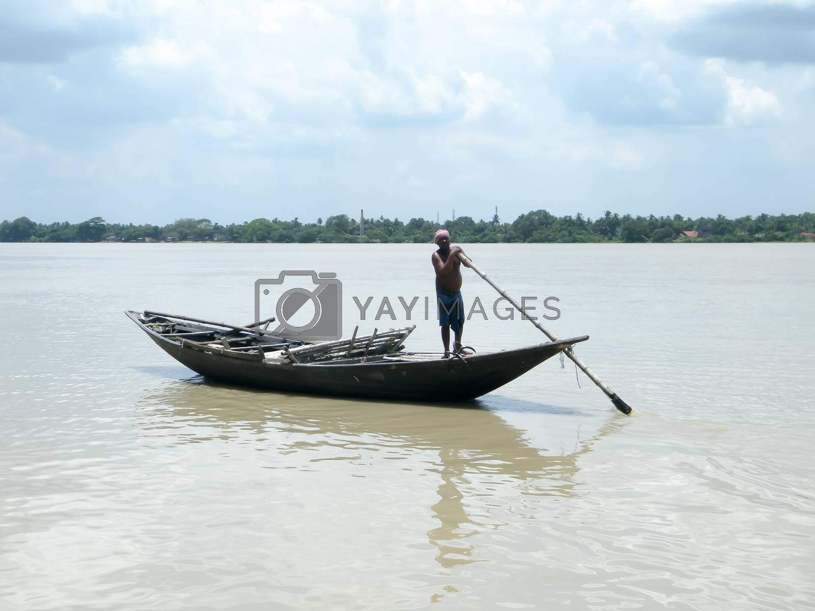 Royalty free image of Traditional boatman (ferry people Majhi) rowing boat (called Nauka) on river Ganges (Ganga). Rural Indian travel tourism and water transportation theme. The Sundarbans West Bengal India South Asia Pac by sudiptabhowmick