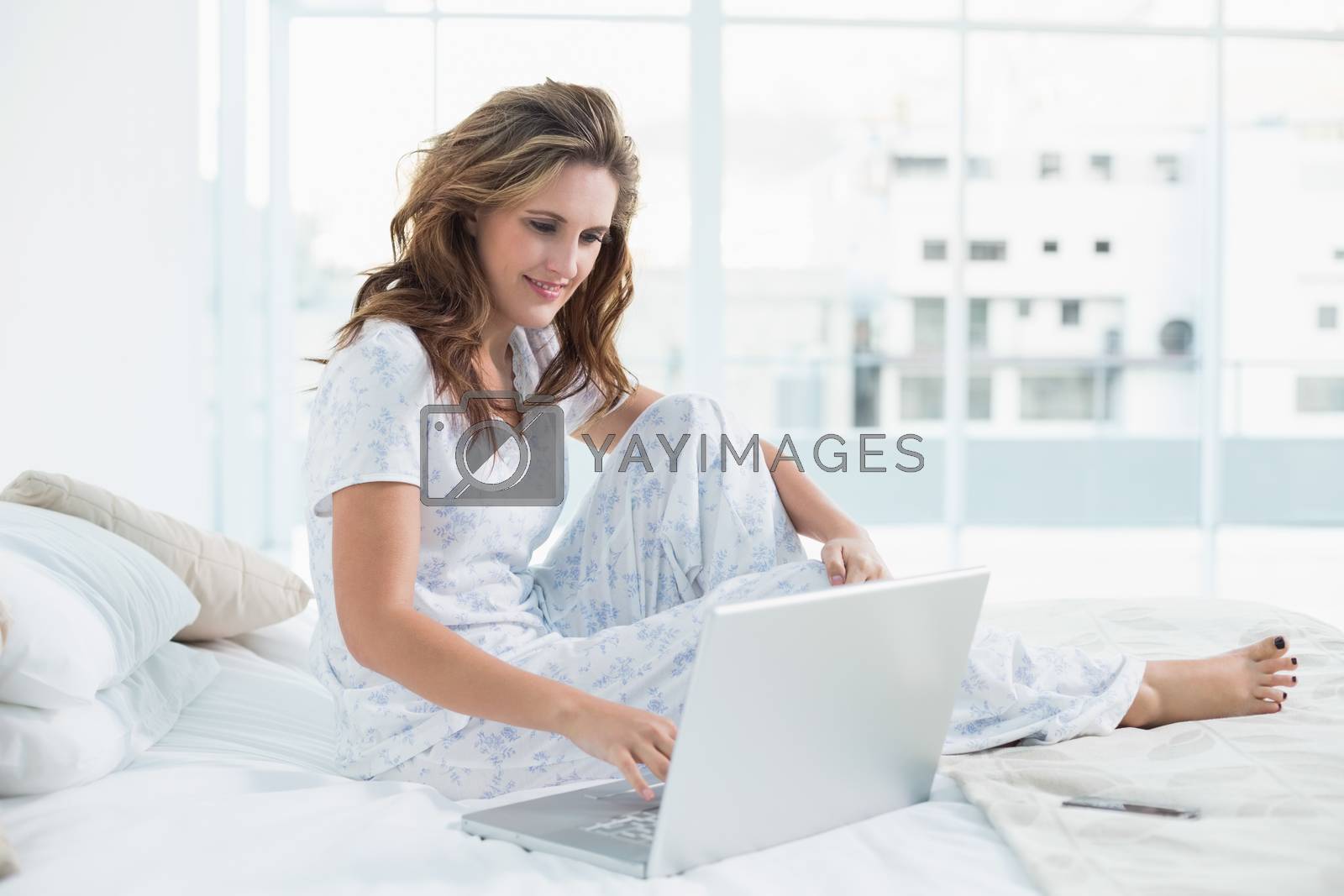 Royalty free image of Young woman sitting on cosy bed by Wavebreakmedia
