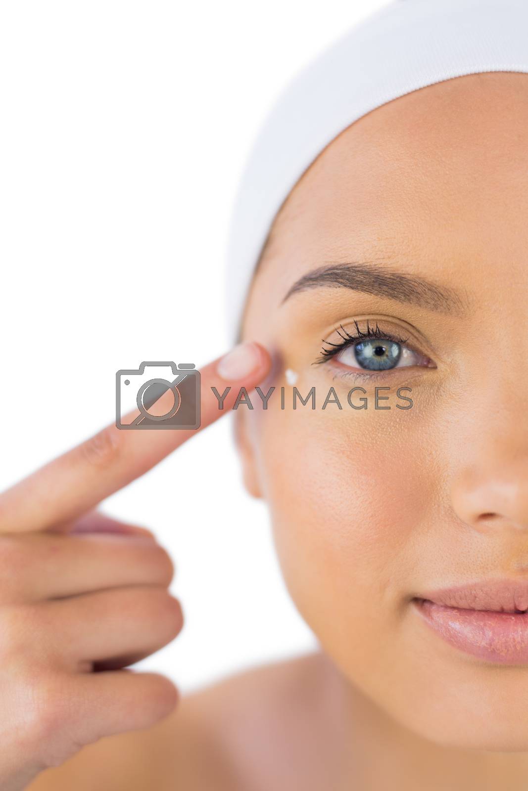 Royalty free image of Attractive woman with headband on putting cream on her face by Wavebreakmedia