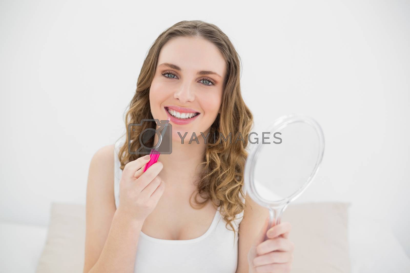 Royalty free image of Smiling woman using lip gloss  by Wavebreakmedia