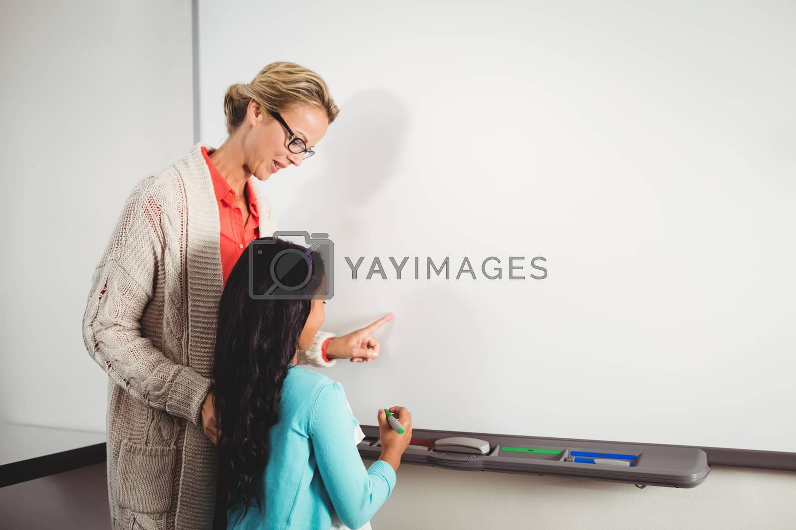 Royalty free image of Teacher and pupil standing in front of whiteboard by Wavebreakmedia