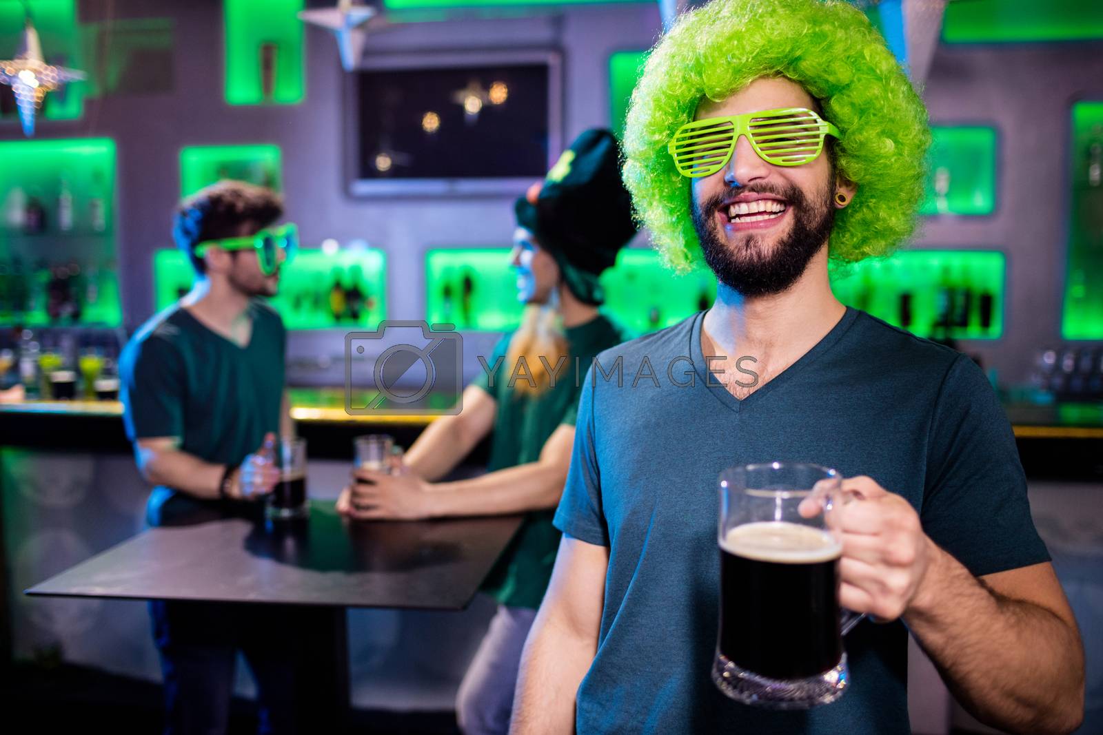 Royalty free image of Man holding beer glass and smiling by Wavebreakmedia