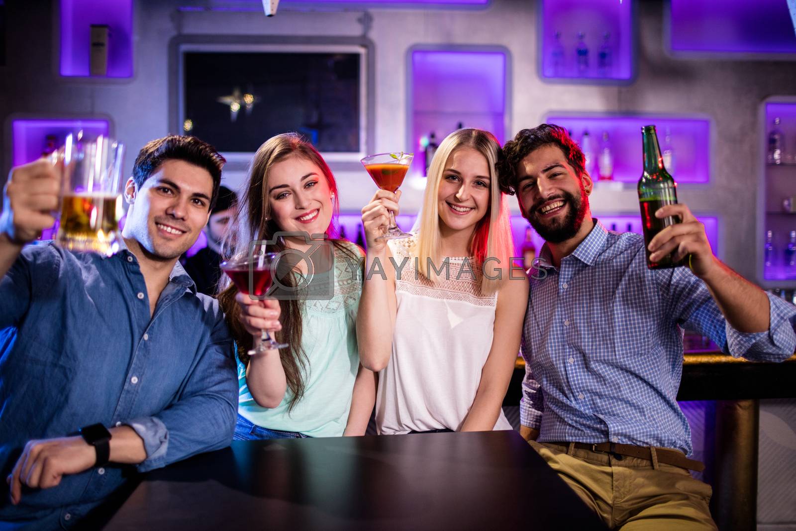 Royalty free image of Group of friends showing cocktail, beer bottle and beer glass at bar counter by Wavebreakmedia