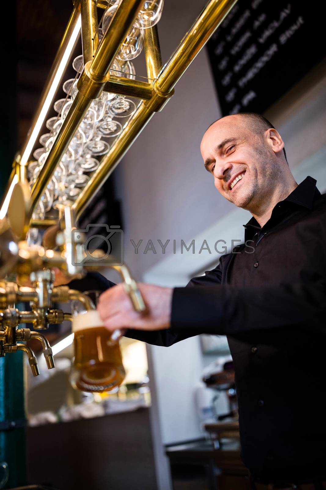 Royalty free image of Brewer filling beer in beer glass from beer pump by Wavebreakmedia