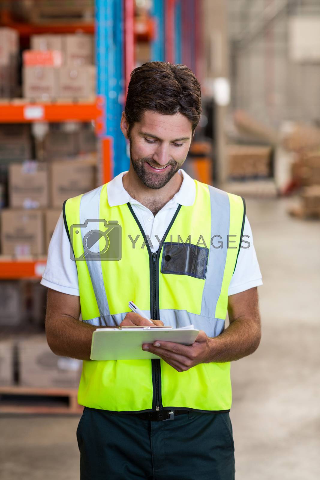 Royalty free image of Portrait of worker is writing on clipboard by Wavebreakmedia
