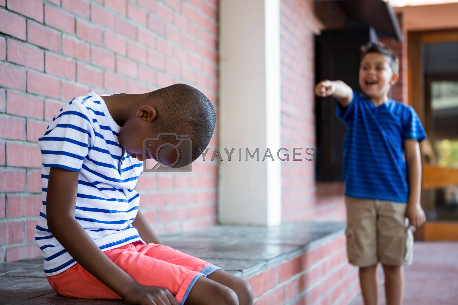Royalty free image of Boy laughing on sad classmate in corridor by Wavebreakmedia