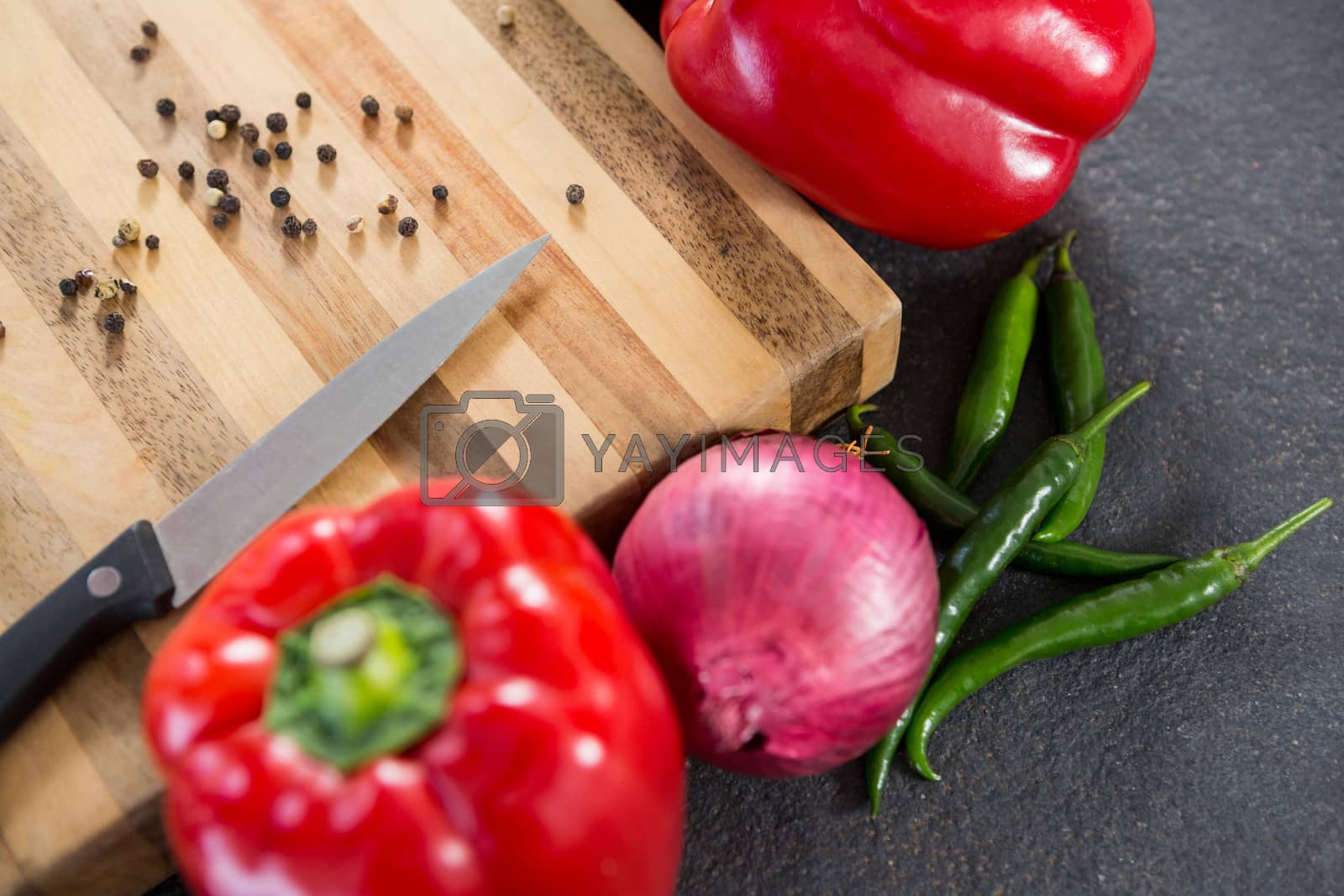 Royalty free image of Bell pepper, onion, chillies and knife on wooden board by Wavebreakmedia