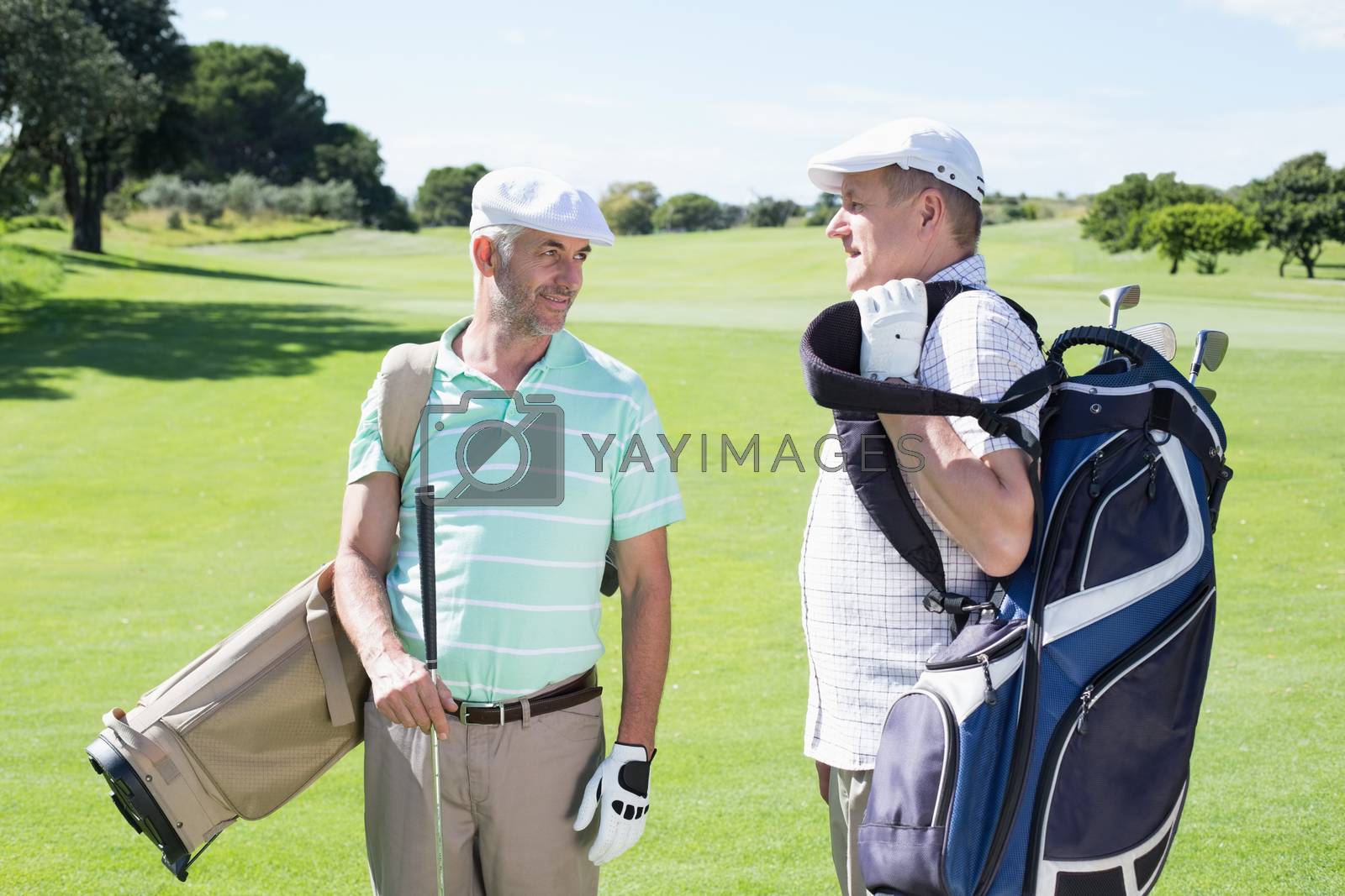 Royalty free image of Golfer friends chatting and holding their golf bags by Wavebreakmedia