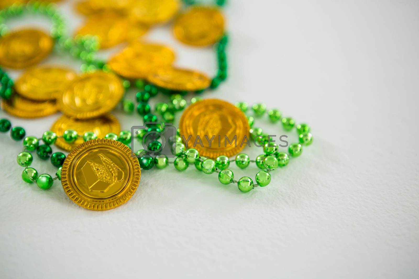 Royalty free image of St Patricks Day gold chocolate coin and beads by Wavebreakmedia