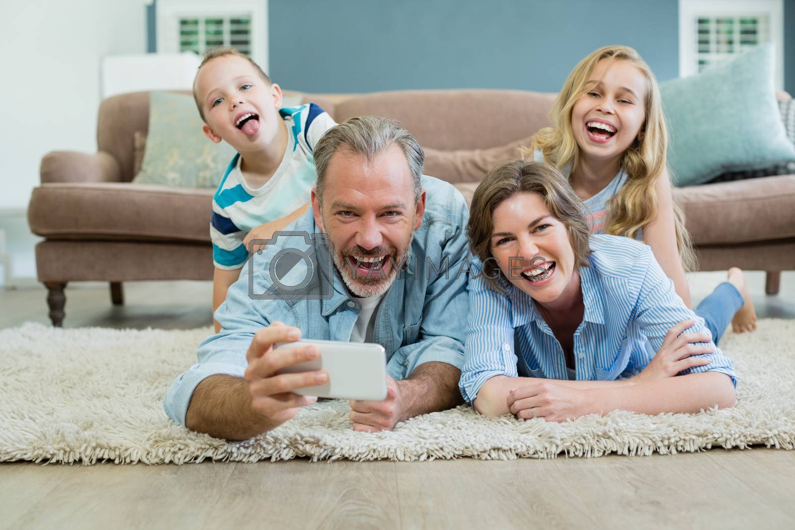 Royalty free image of Family taking selfie while lying together on the carpet by Wavebreakmedia