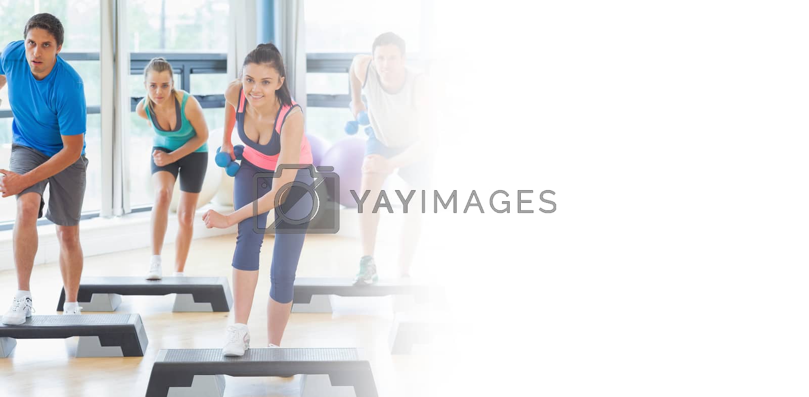 Royalty free image of Class performing step aerobics exercise with dumbbells by Wavebreakmedia