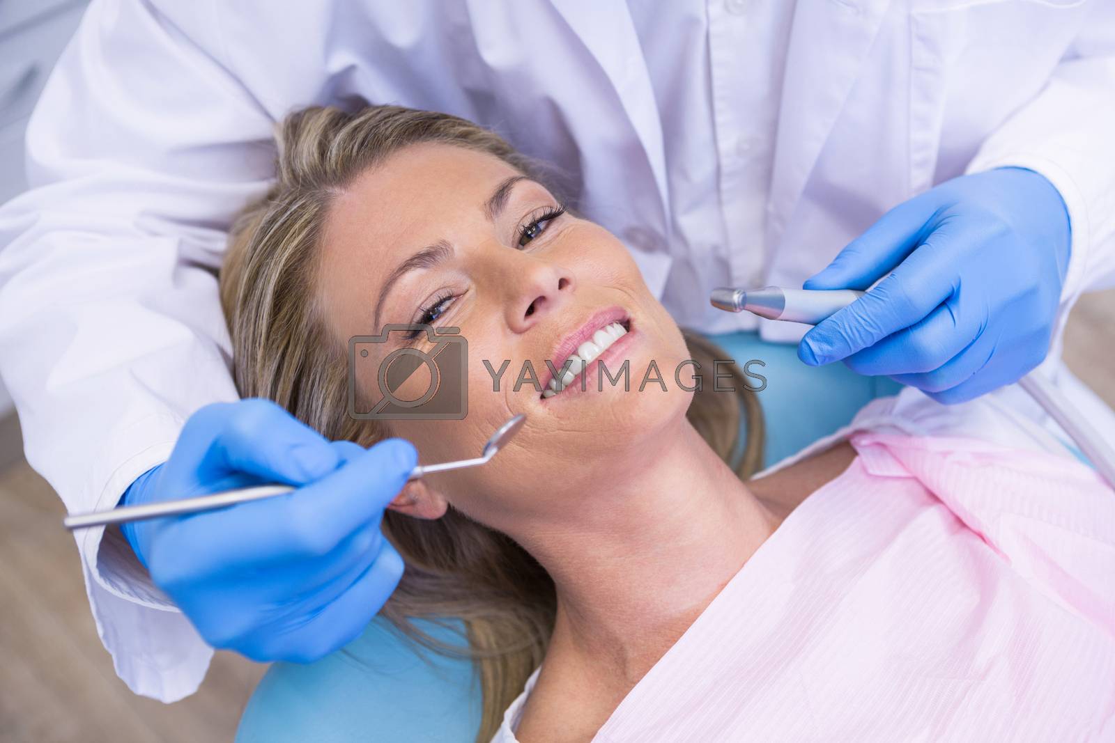 Royalty free image of High angle portrait of woman by dentist dolding tool by Wavebreakmedia