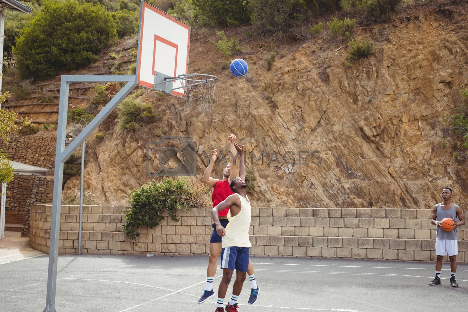 Royalty free image of Basketball players playing in basketball court by Wavebreakmedia