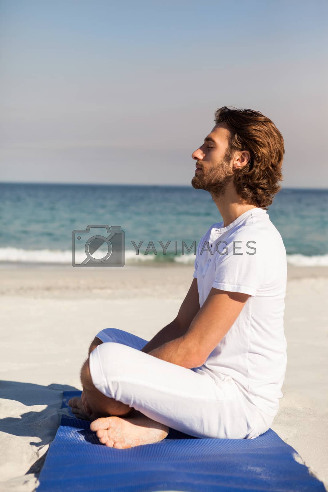 Royalty free image of Man performing yoga at beach by Wavebreakmedia