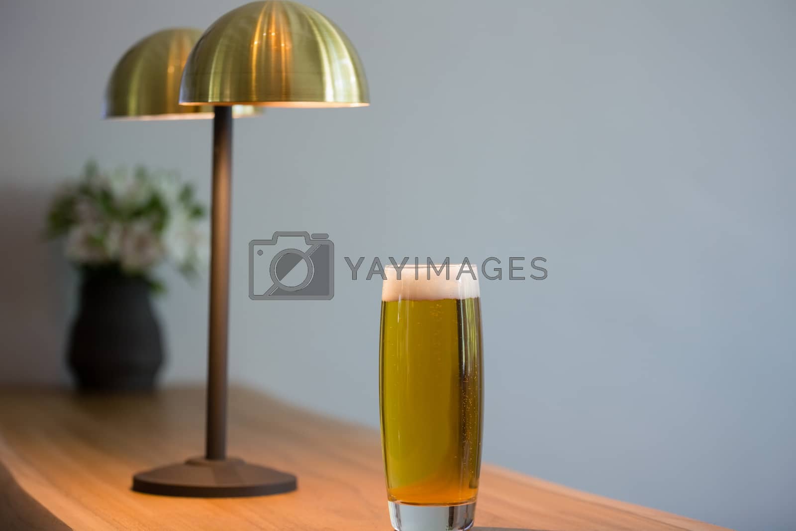 Royalty free image of Close up of beer glass by lighting equipment in restaurant by Wavebreakmedia