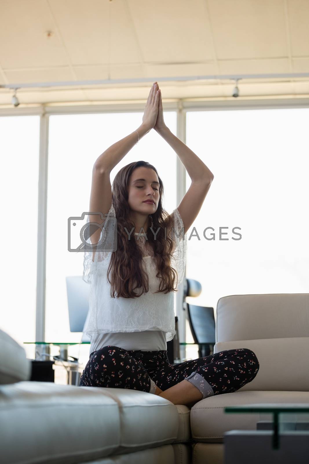 Royalty free image of Young businesswoman doing yoga at office by Wavebreakmedia