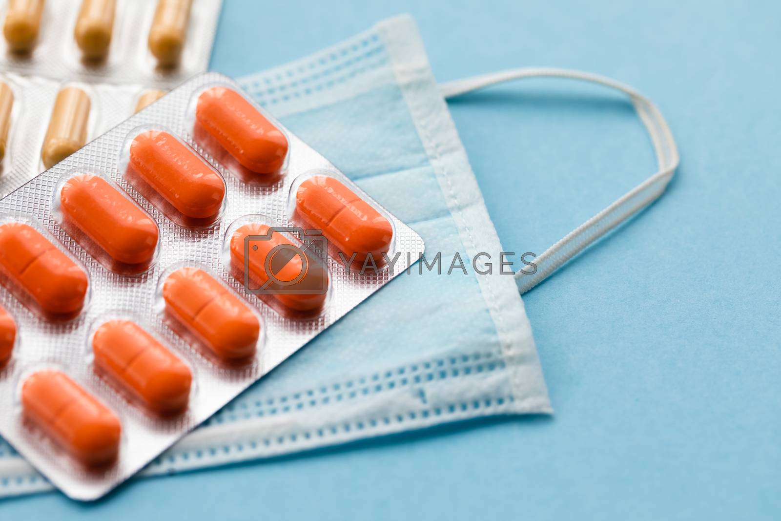 Royalty free image of Tablets and pills on blue background with surgical protective mask, medicine drugs concept by Katia1504