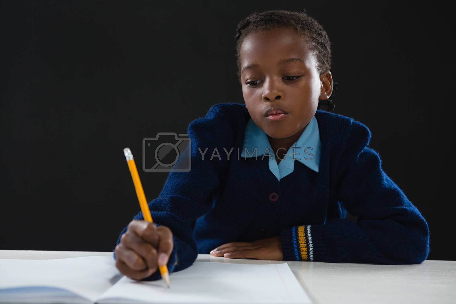 Royalty free image of Schoolgirl doing her homework against black background by Wavebreakmedia
