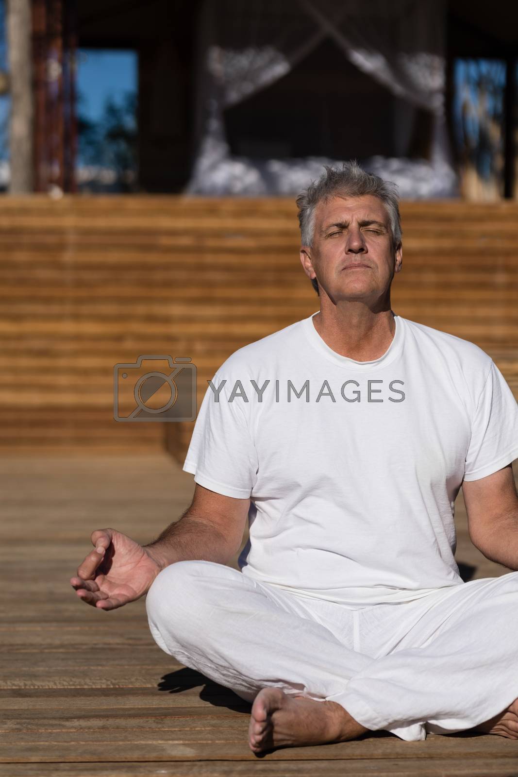 Royalty free image of Man practicing yoga on wooden plank by Wavebreakmedia