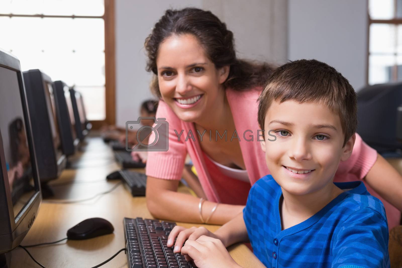 Royalty free image of Cute pupils in computer class with teacher by Wavebreakmedia