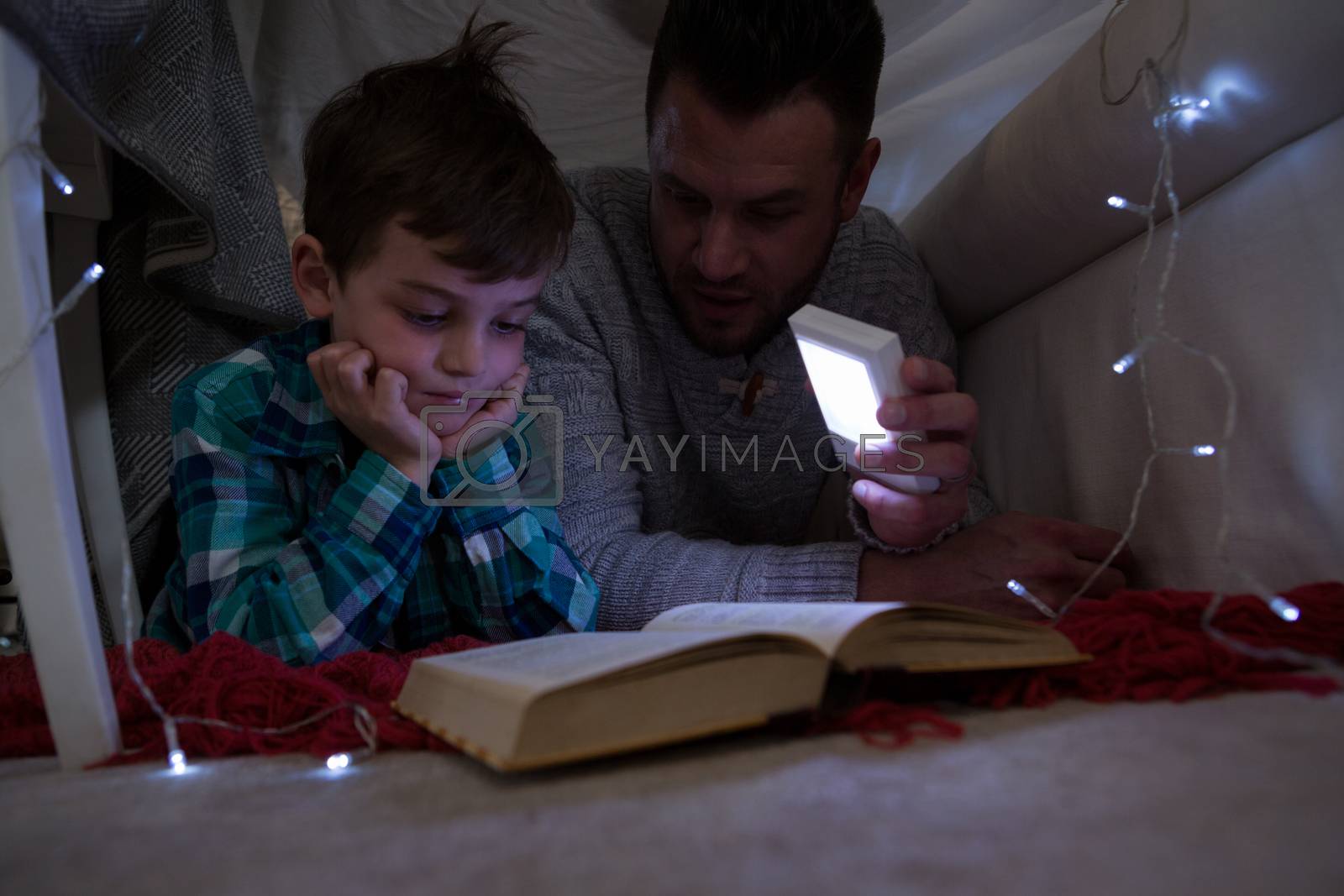 Royalty free image of Father and son reading book under shelter by Wavebreakmedia