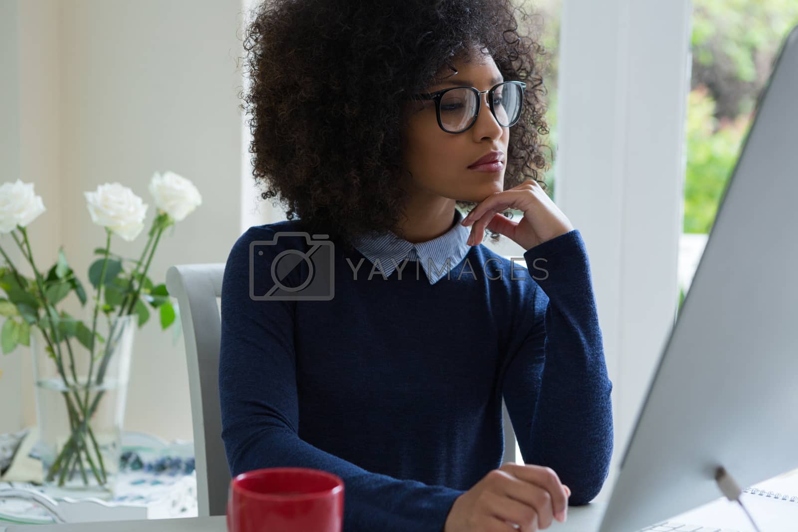 Royalty free image of Thoughtful woman working on desktop pc at desk by Wavebreakmedia