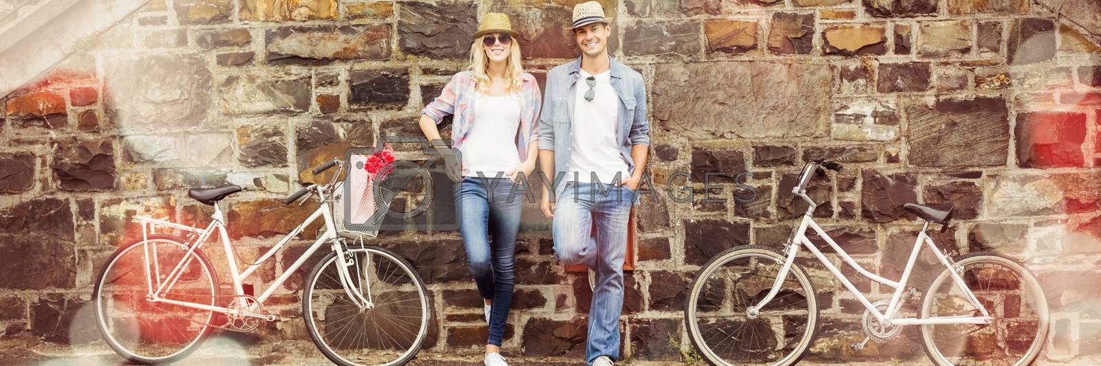 Royalty free image of Hip young couple standing by brick wall with their bikes by Wavebreakmedia