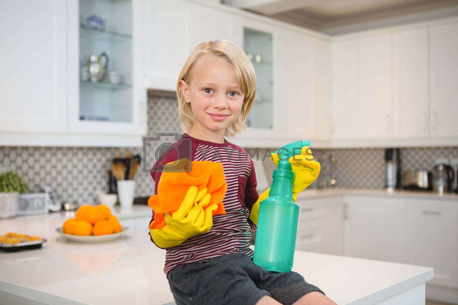 Royalty free image of Boy holding rag and spray bottle in kitchen by Wavebreakmedia