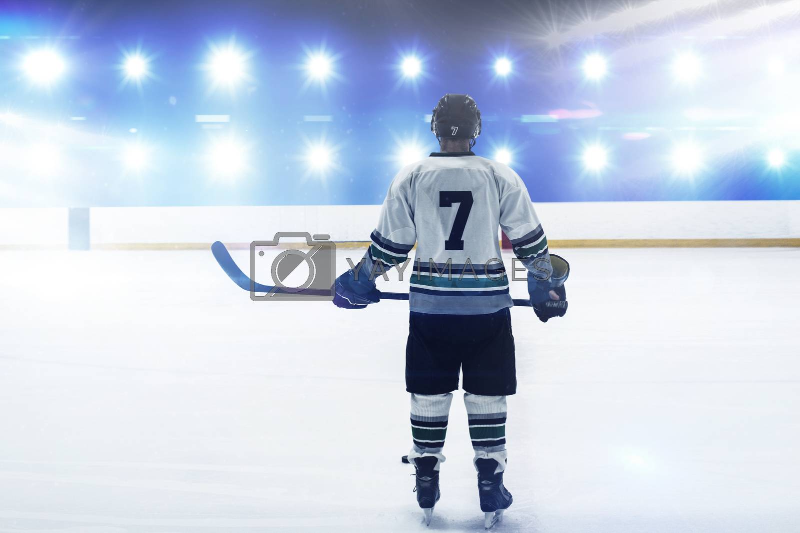 Royalty free image of Composite image of hockey player with hockey stick standing on rink by Wavebreakmedia